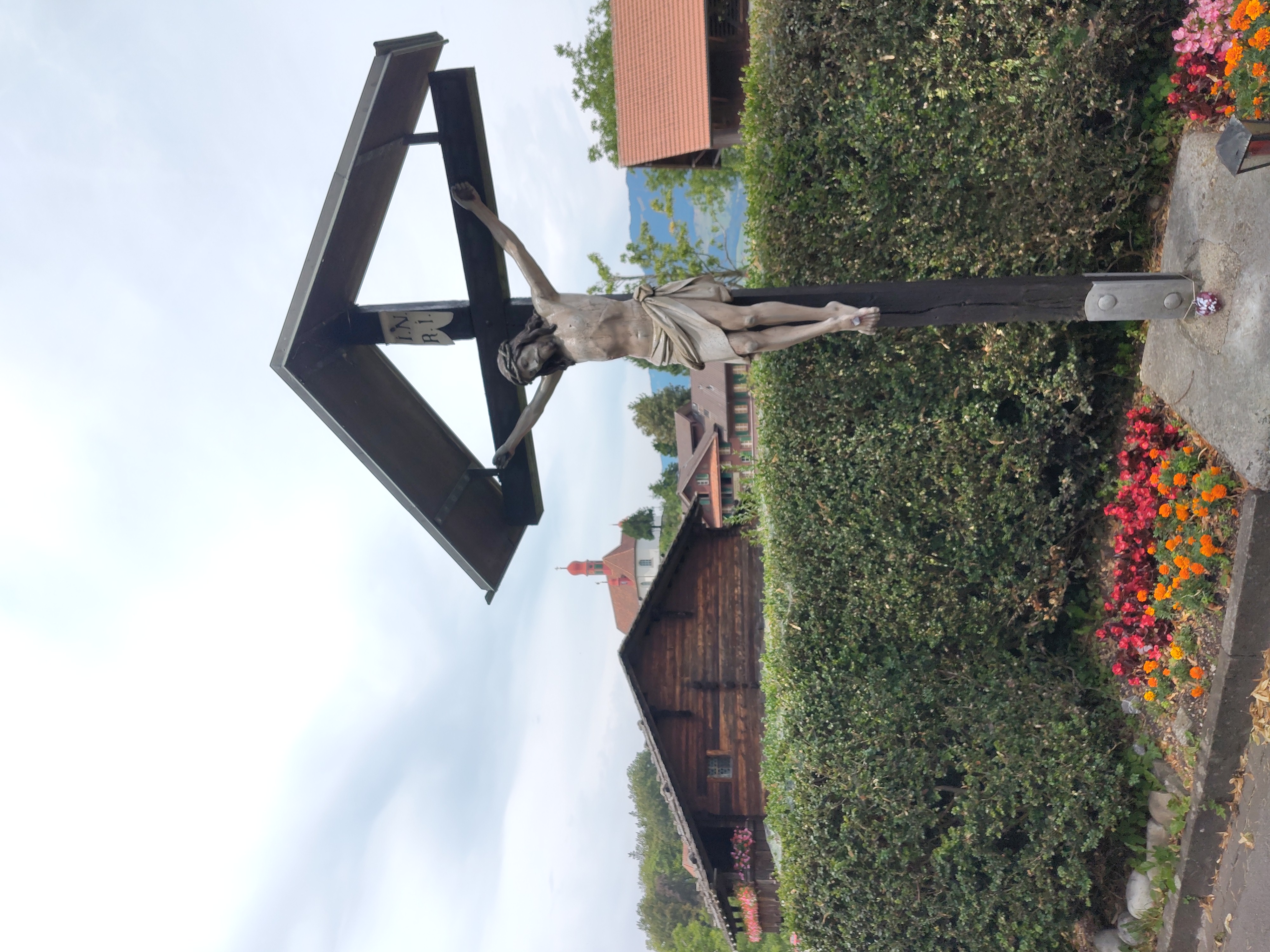 Wegkreuz, im Hintergrund das Wohnhaus von Niklaus und Dorothee, sowie die Kapelle Karl Borromäus Wegkreuz, im Hintergrund das Wohnhaus von Niklaus und Dorothee, sowie die Kapelle Karl Borromäus